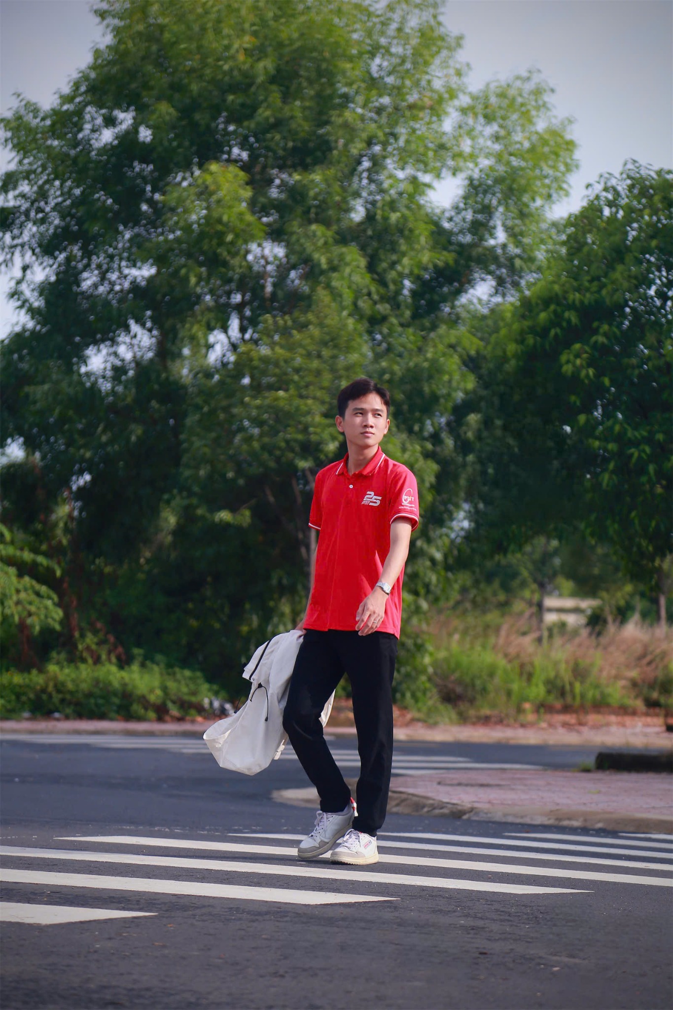 Nguyễn Thanh Tùng đứng ngoài trời trong áo polo đỏ